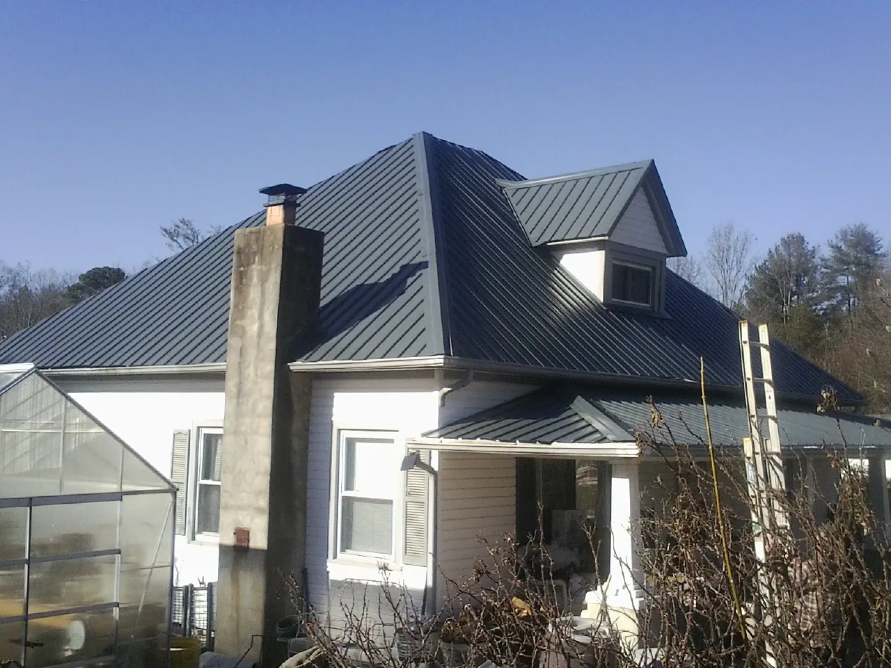 Dark blue standing seam metal roof on a white farmhouse with dormer — Slate & Tile Roof Repair by Roofing Brothers in Schenectady