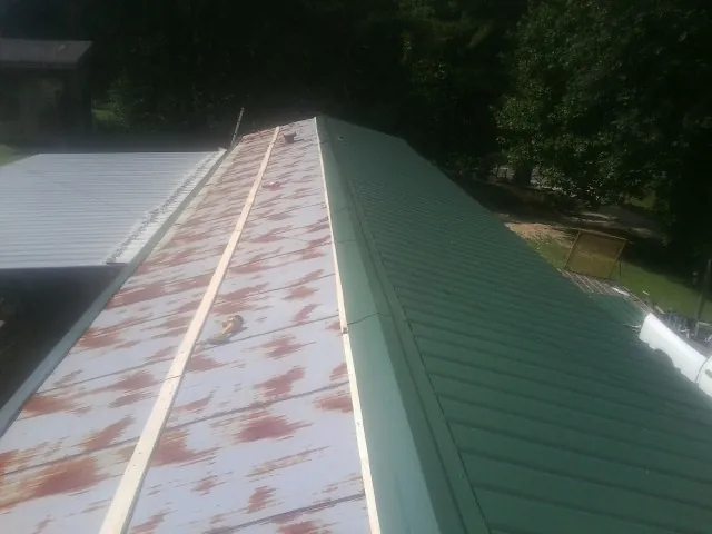 Old rusted panels beside newly installed green metal roofing — Wind Damage Roof Repair by Roofing Brothers in Schenectady