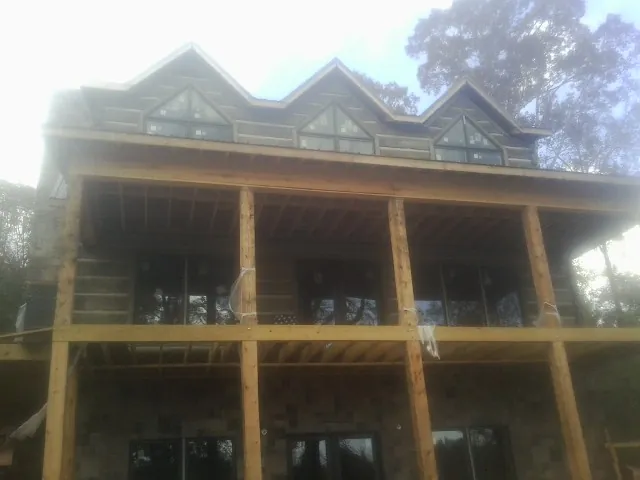 Dormers and porch framing on a large log home under construction — Roof Coating work by our crew in Schenectady