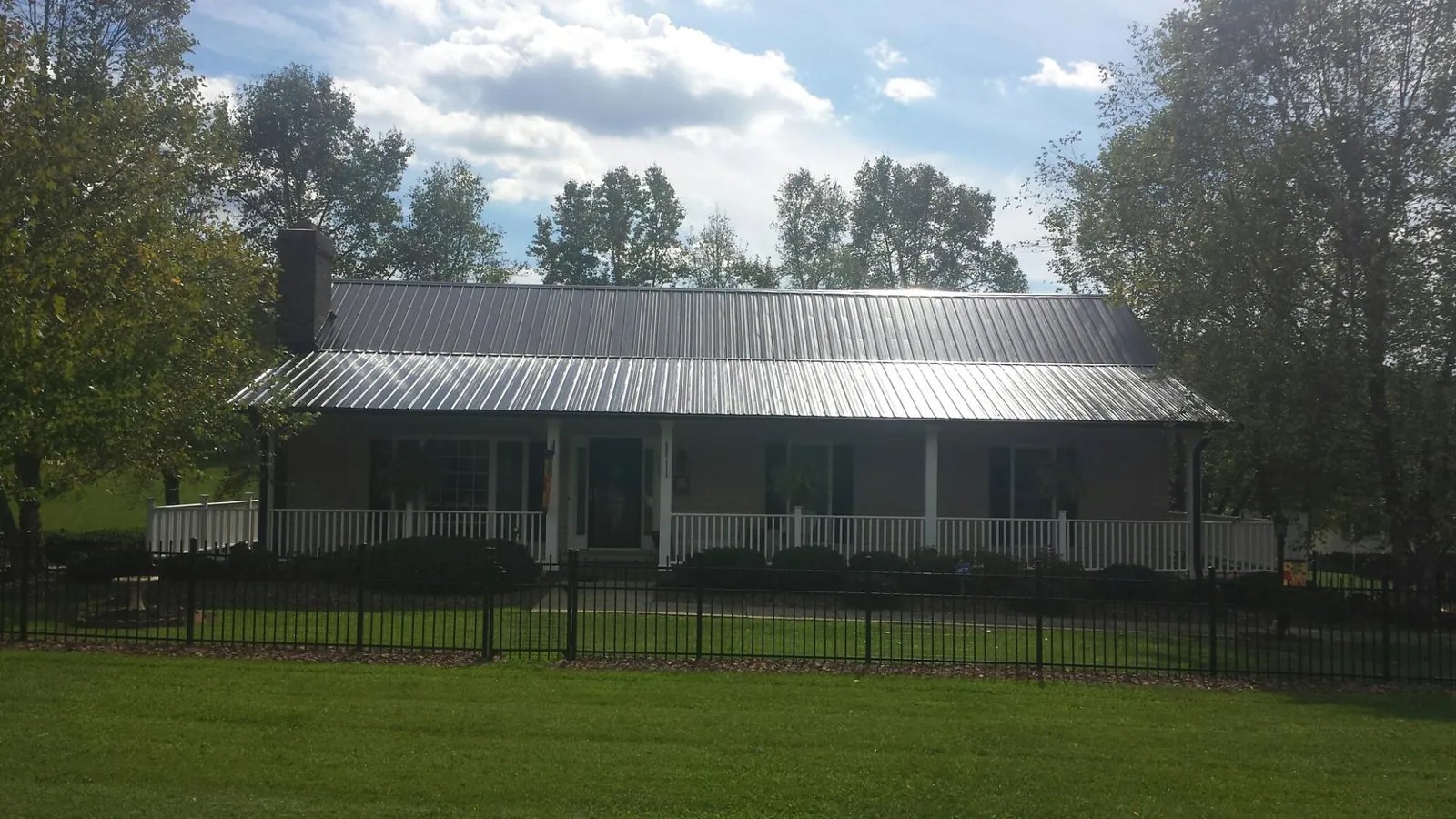 Gray metal roof on a brick ranch with a full width front porch — Gutter Guard Installation work by our crew in Schenectady