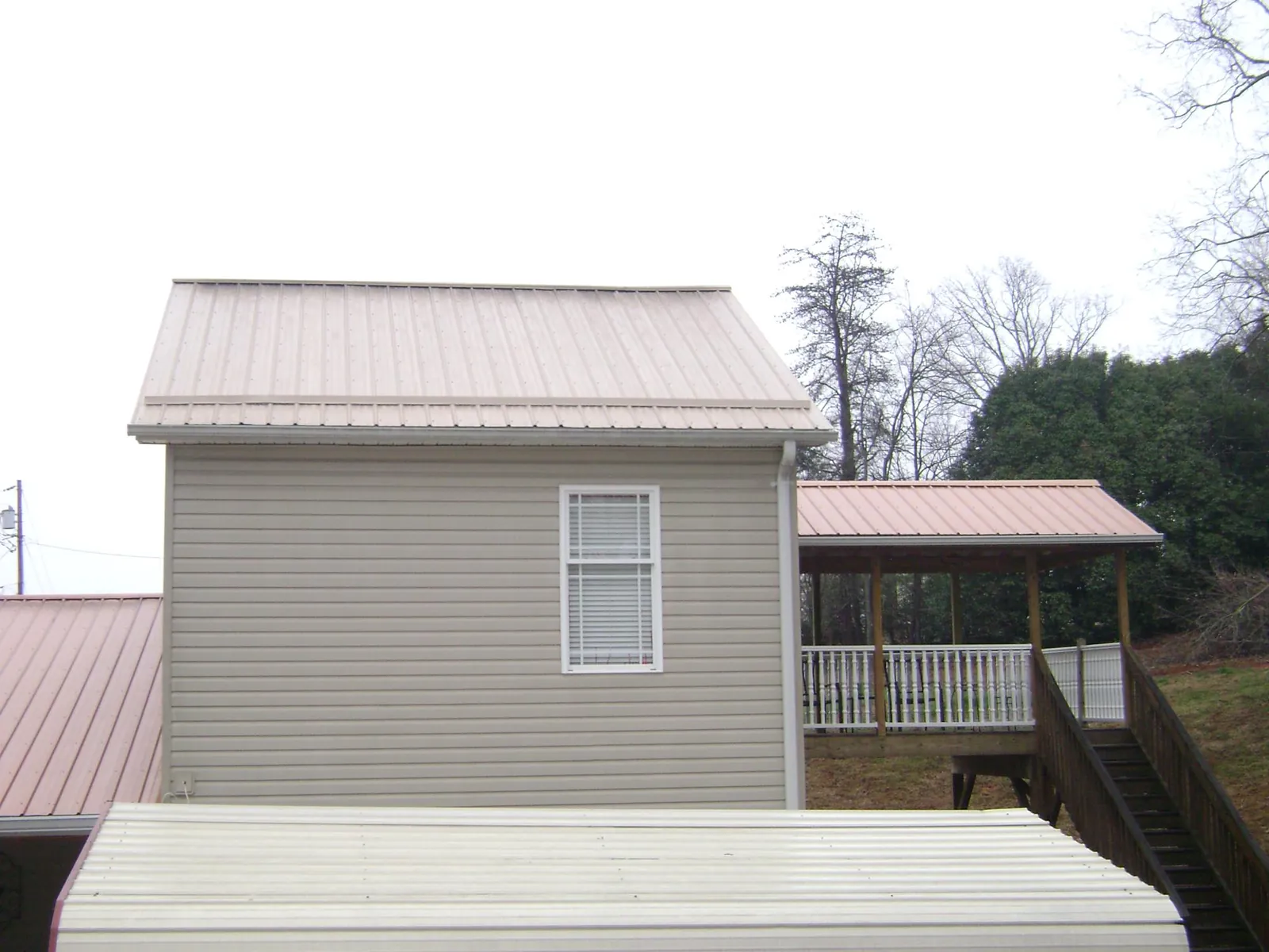 Tan metal roofs on a two story addition and attached porch, from a Roof Replacement job in Schenectady