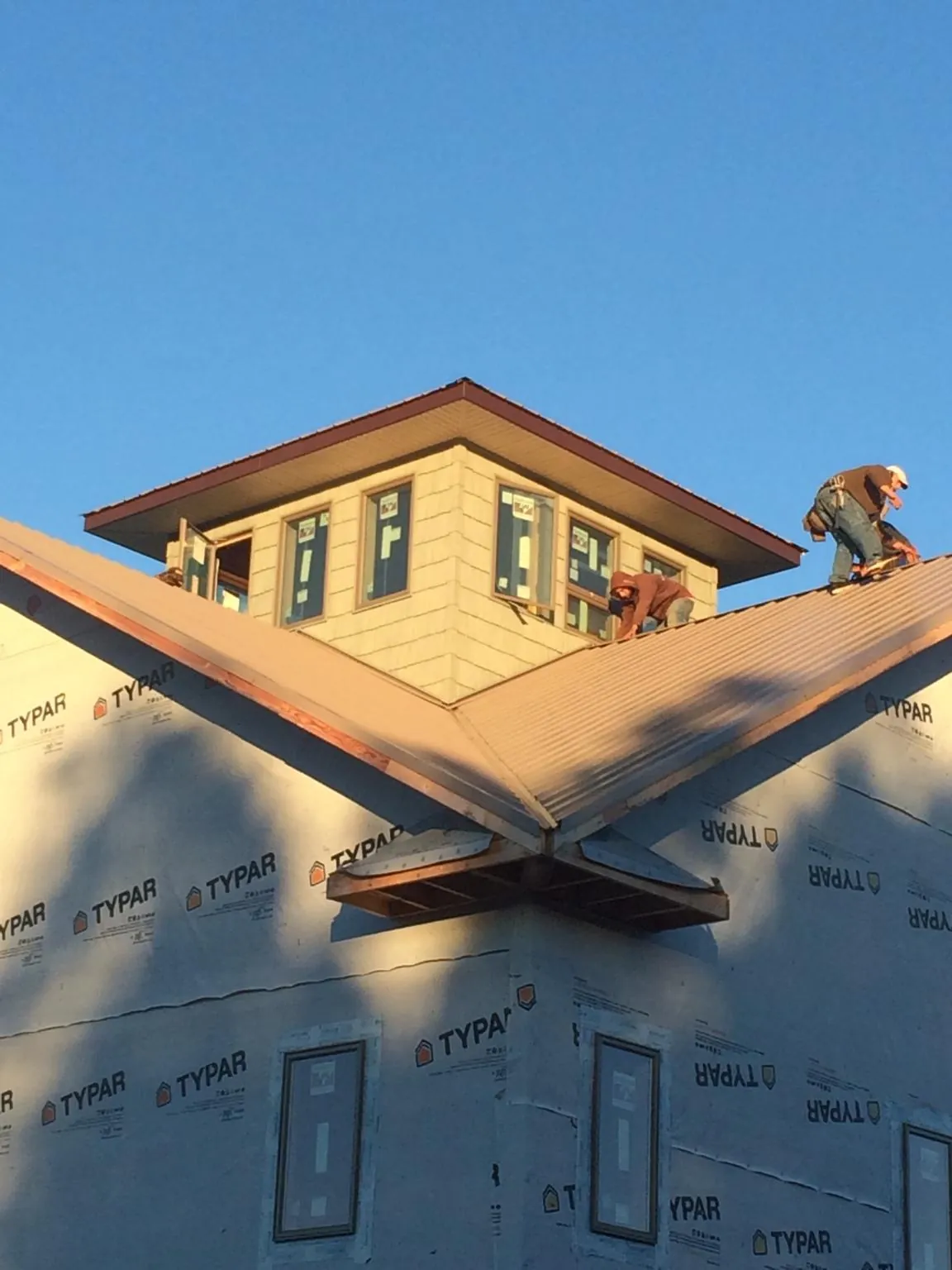 Roofers working around a rooftop cupola on a new metal roof at sunset — Roof Waterproofing in Schenectady by Roofing Brothers